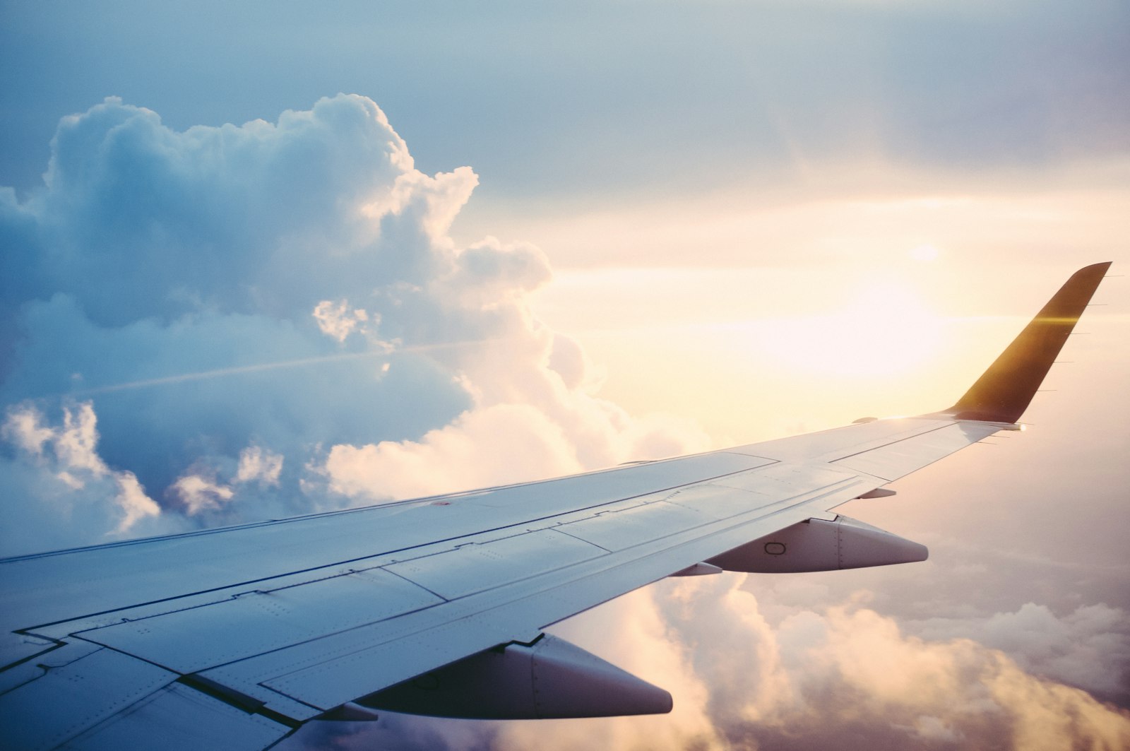 Airplane wing and clouds at sunset — mid-year award travel booking window
